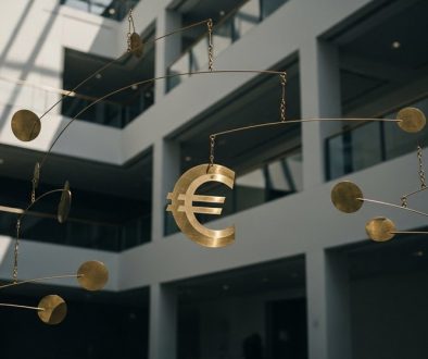 Eine große, ausbalancierte Messingskulptur mit Euro-Symbol, die das Mandat der EZB für Preisstabilität symbolisiert.